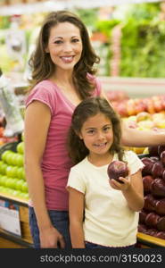 Woman and daughter shopping for apples at a grocery store