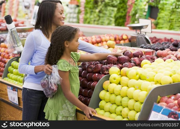 Woman and daughter shopping for apples at a grocery store