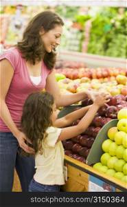 Woman and daughter shopping for apples at a grocery store