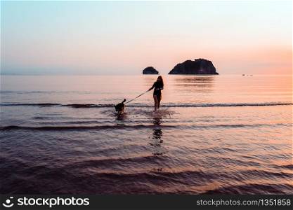 Woman and dog on beach at sunrise