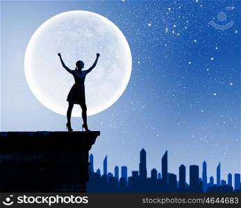 Woman and full moon. Silhouette of woman on top of building at night