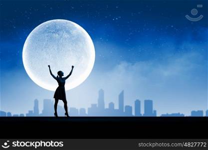Woman and full moon. Silhouette of woman on top of building at night