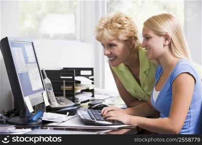Woman and girl in home office with computer smiling