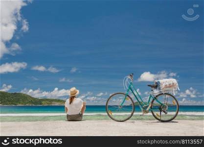 Woman and her bicycle at teh beach in Seychelles