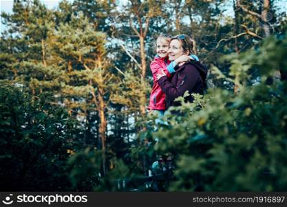 Woman and her dughter admiring landscape actively spending summer vacation together walking down a forest path. Active people spending time outdoors in a forest
