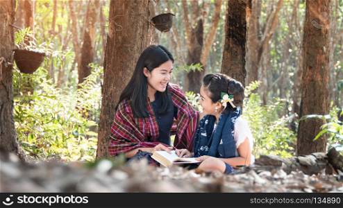 woman and her little girl relaxing . Asian woman and her little girl relaxing in Rubber plantation