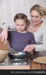 Woman and little girl cooking pancakes