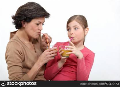 Woman and little girl drinking orange juice
