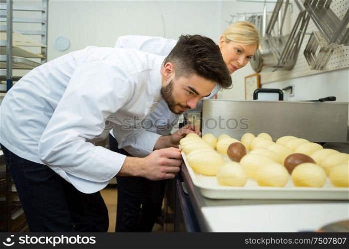 woman and man busy preparing a chocolate eggs