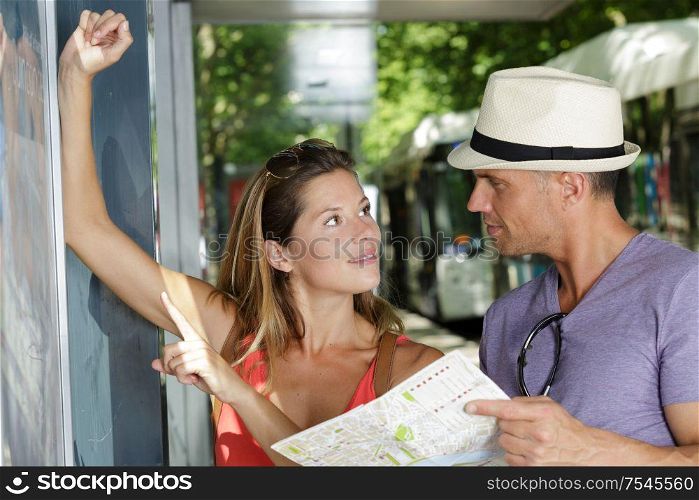woman and man checking a bus at bus stop