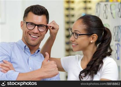 woman and man choosing her new glasses at optics store
