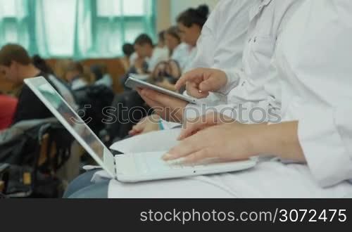 Woman and man doctors or medical students using laptop and digital tablet during the lecture or conference