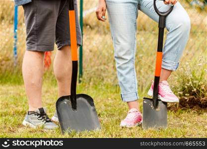Woman and man gardener digging hole in ground soil with shovel. Yard work around the house. Woman and man digging hole in garden