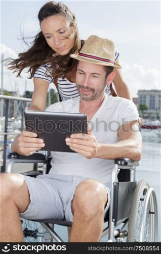 woman and man in wheelchair using tablet