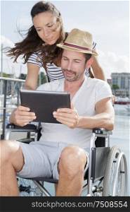 woman and man in wheelchair using tablet