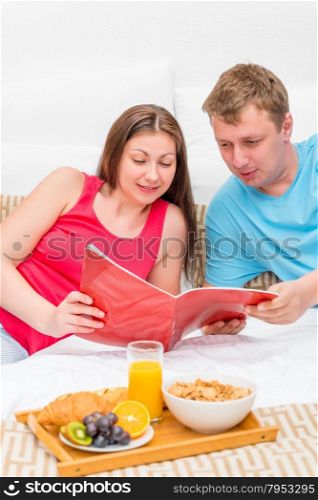 woman and man looking a magazine in bed in the morning