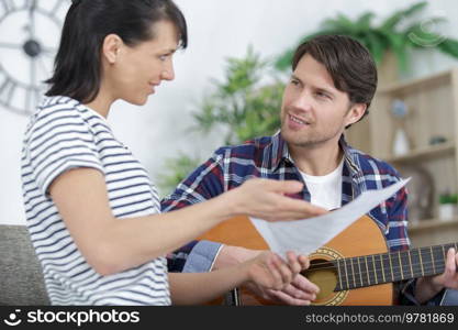 woman and man playing guitar composting melody