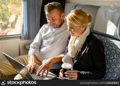 Woman and man relaxing in train laptop smiling commuters travel
