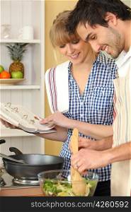 Woman and man smiling cooking using cookbook