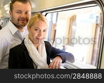 Woman and man standing by train window smiling commuters travel
