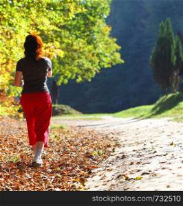 Woman and man walking cross country and trail in autumn forest