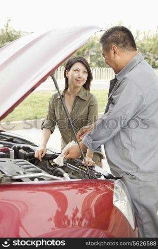 Woman and Mechanic Working on Car