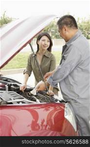 Woman and Mechanic Working on Car