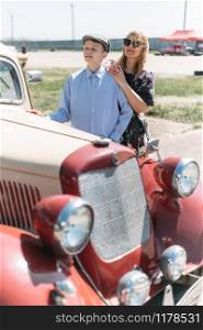 Woman and teenage boy in retro style near old car
