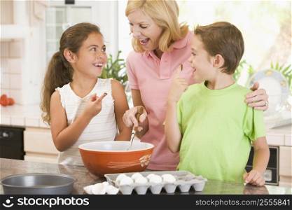 Woman and two children in kitchen baking and smiling