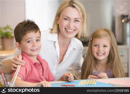 Woman and two young children in kitchen with art project smiling