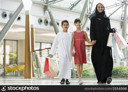 Woman and two young children walking in mall smiling (selective focus)