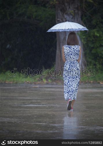 woman and umbrella lonely walking in raining field