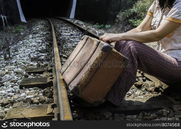 Woman and vintage suitcase on railway road and tunnel.