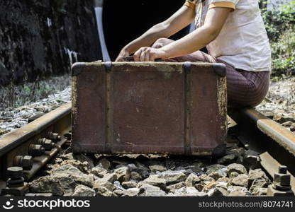 Woman and vintage suitcase on railway road and tunnel.