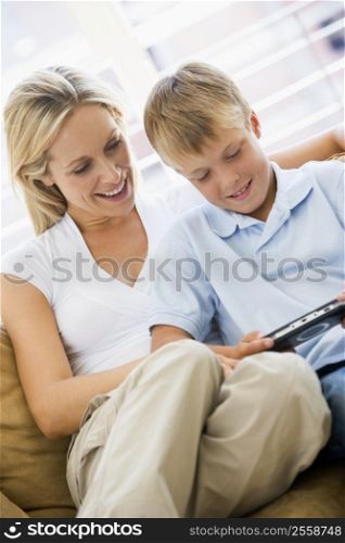 Woman and young boy in living room with handheld video game smiling