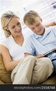 Woman and young boy in living room with handheld video game smiling