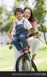 Woman and young boy on a bike outdoors smiling