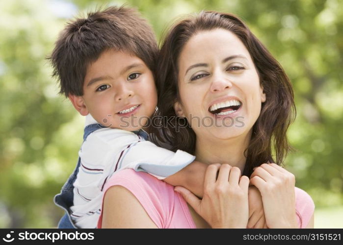 Woman and young boy outdoors embracing and smiling