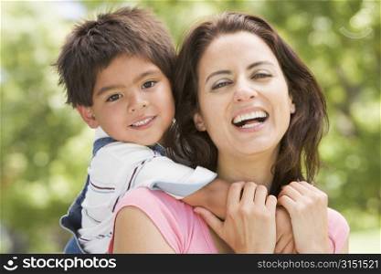 Woman and young boy outdoors embracing and smiling