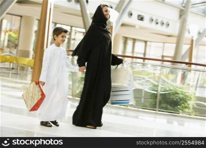 Woman and young boy walking in mall smiling (selective focus)