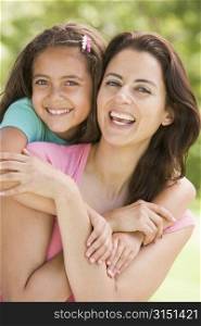 Woman and young girl embracing outdoors smiling