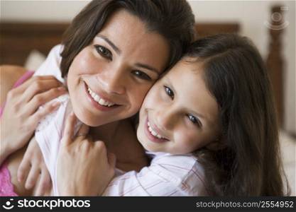 Woman and young girl in bedroom embracing and smiling (selective focus)