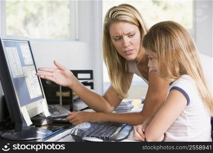 Woman and young girl in home office with computer looking unhappy