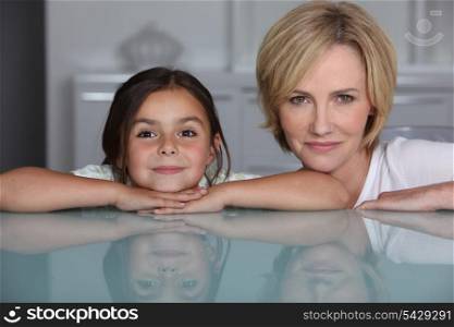 Woman and young girl leaning on glass surface