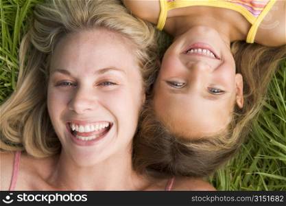 Woman and young girl lying in grass laughing