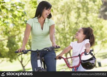 Woman and young girl on bikes outdoors smiling
