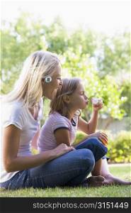 Woman and young girl outdoors blowing bubbles smiling