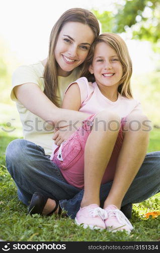 Woman and young girl outdoors embracing and smiling