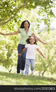 Woman and young girl running outdoors smiling
