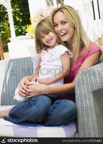 Woman and young girl sitting on patio laughing